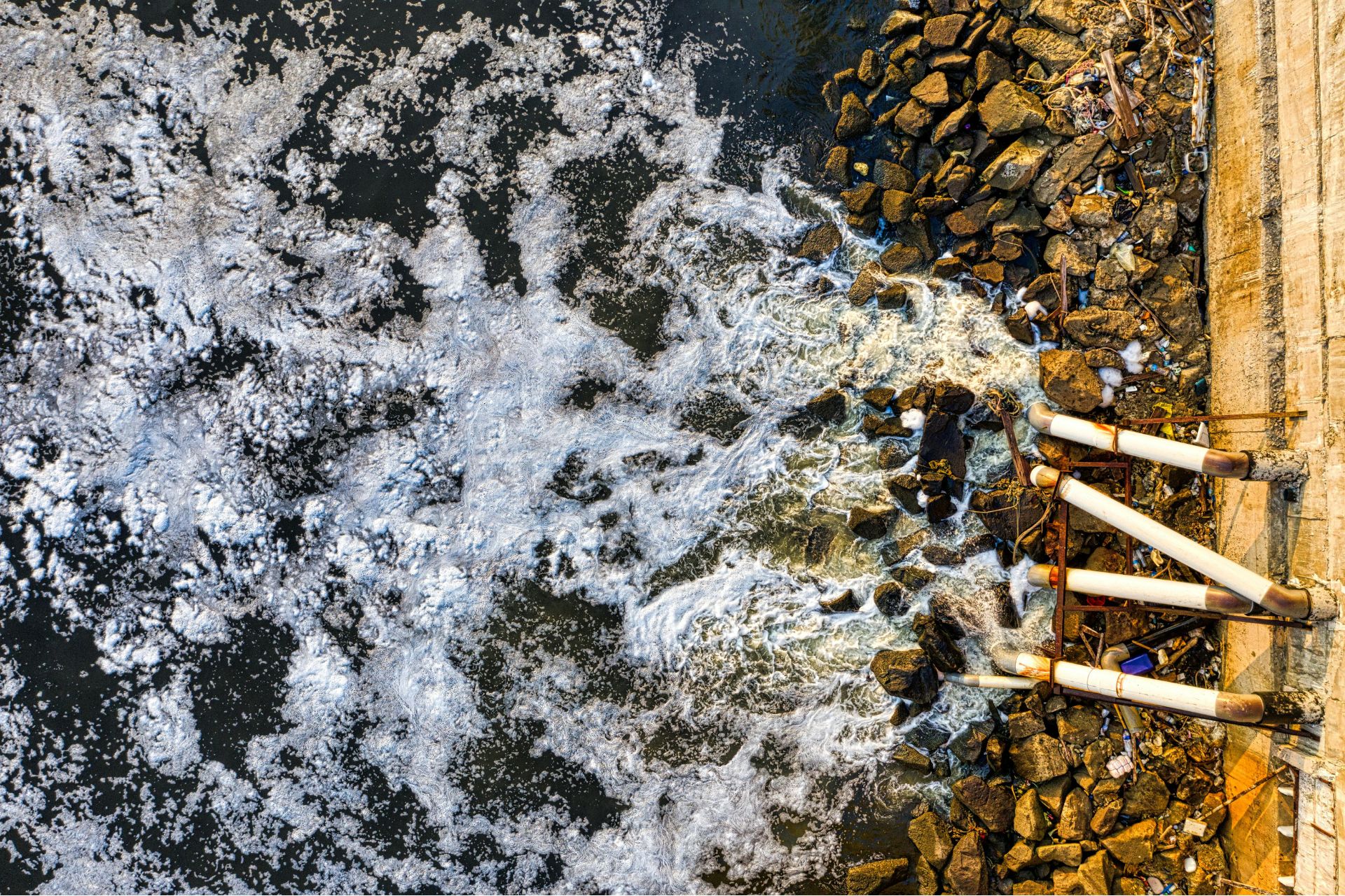 Uitzicht op vervuild water met schuim, symbool voor PFAS-lozingen in de Maas